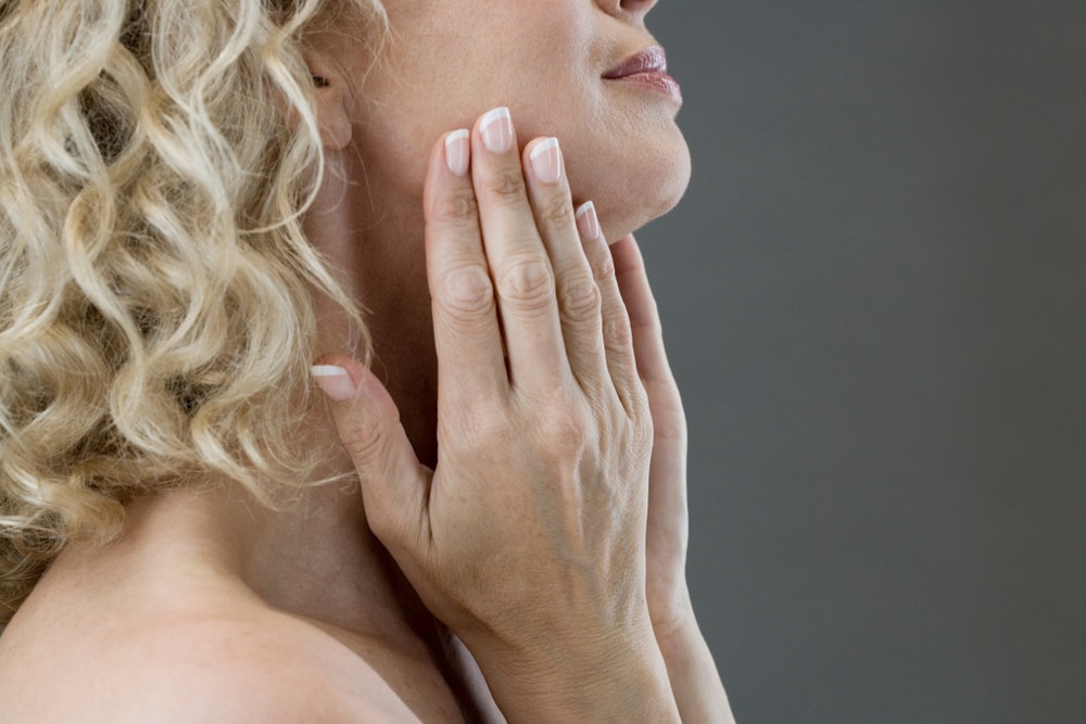 A middle-aged woman looking at her chin in the mirror